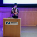 Alex Butler, student at Olin College of Engineering, at a podium presenting his final project.